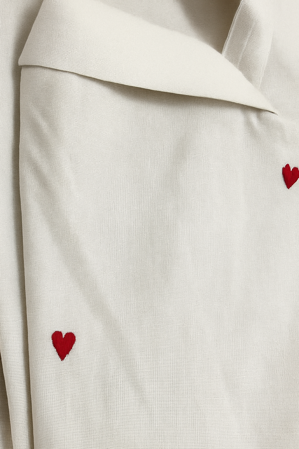 White fabric with red heart shapes embroidered on it