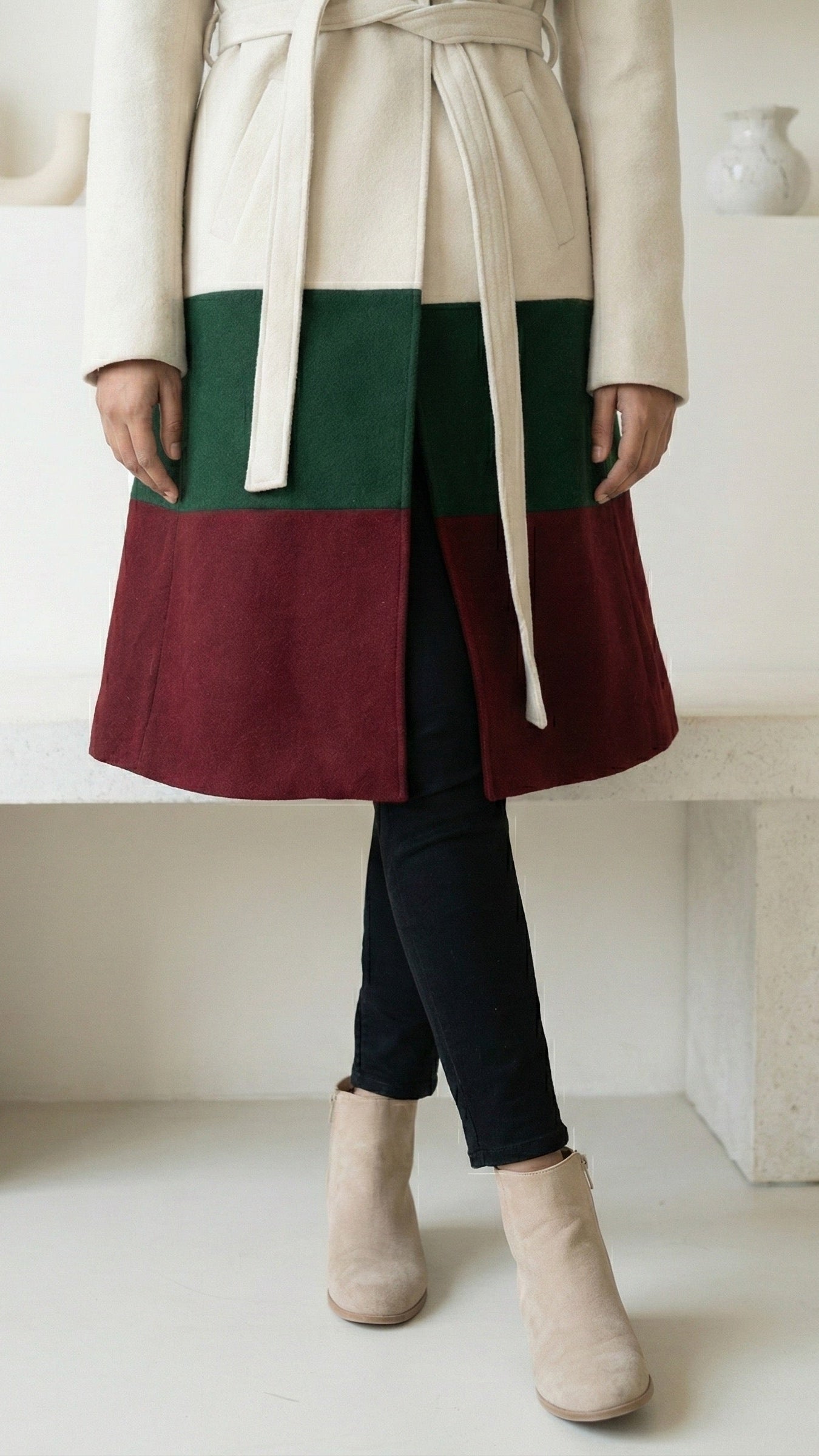 Person wearing a two-tone skirt with a coat in a minimalistic setting