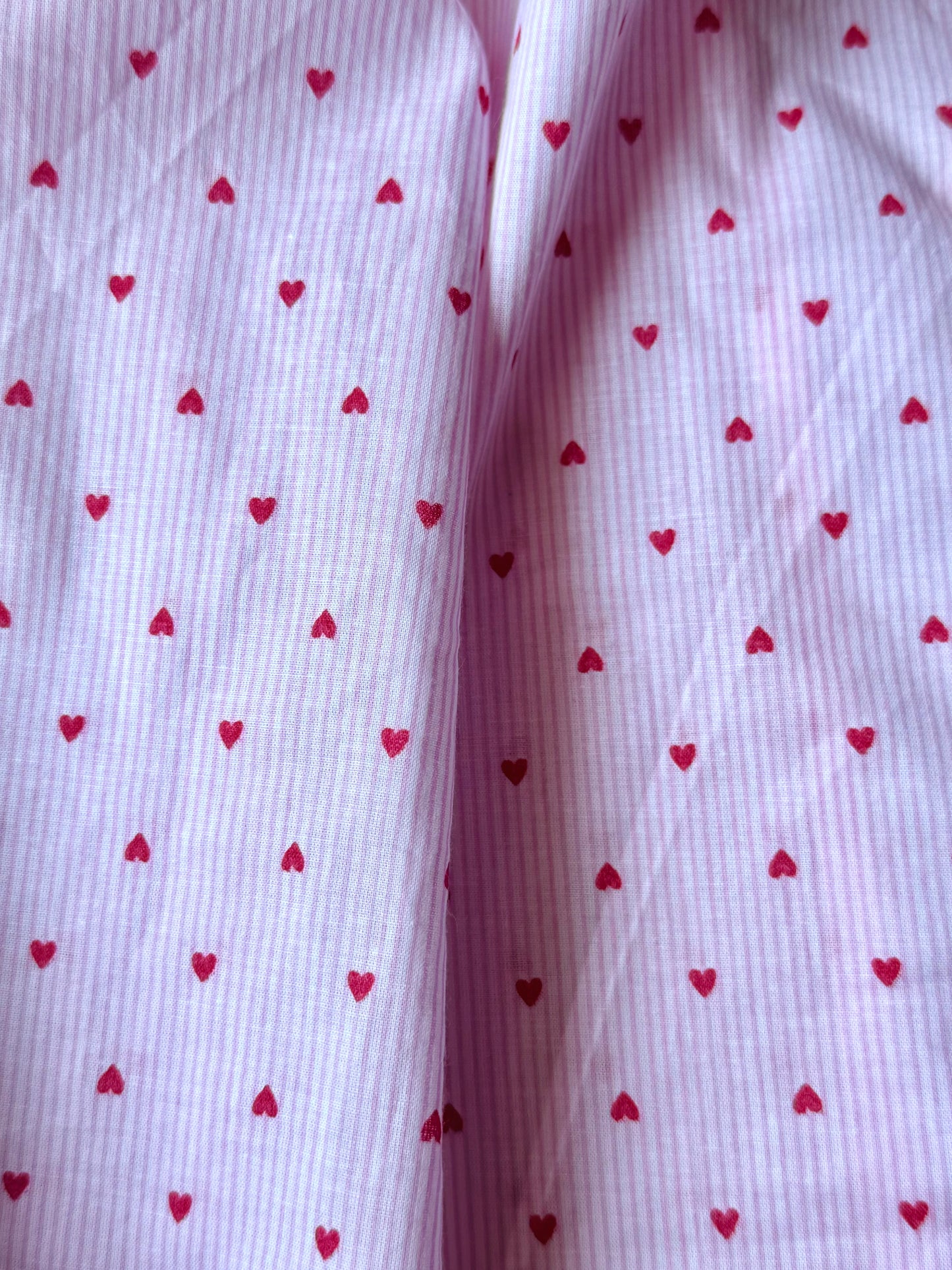Close-up of fabric with red heart patterns on a white background
