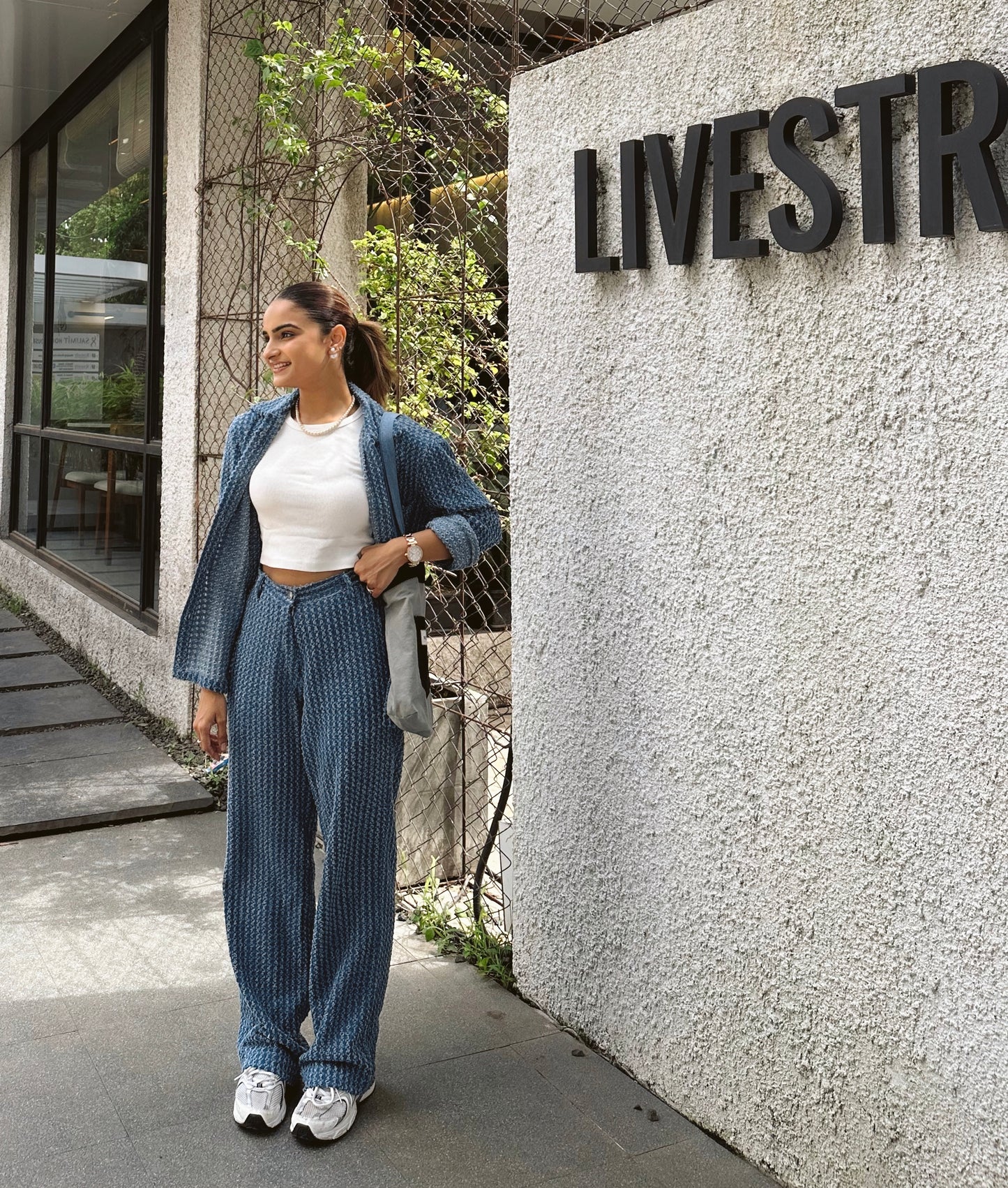 Woman in blue outfit standing next to a building with 'LIVESTR' signage.