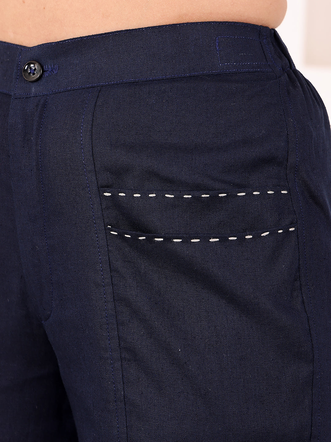 Navy blue pants with a button detail on a beige background