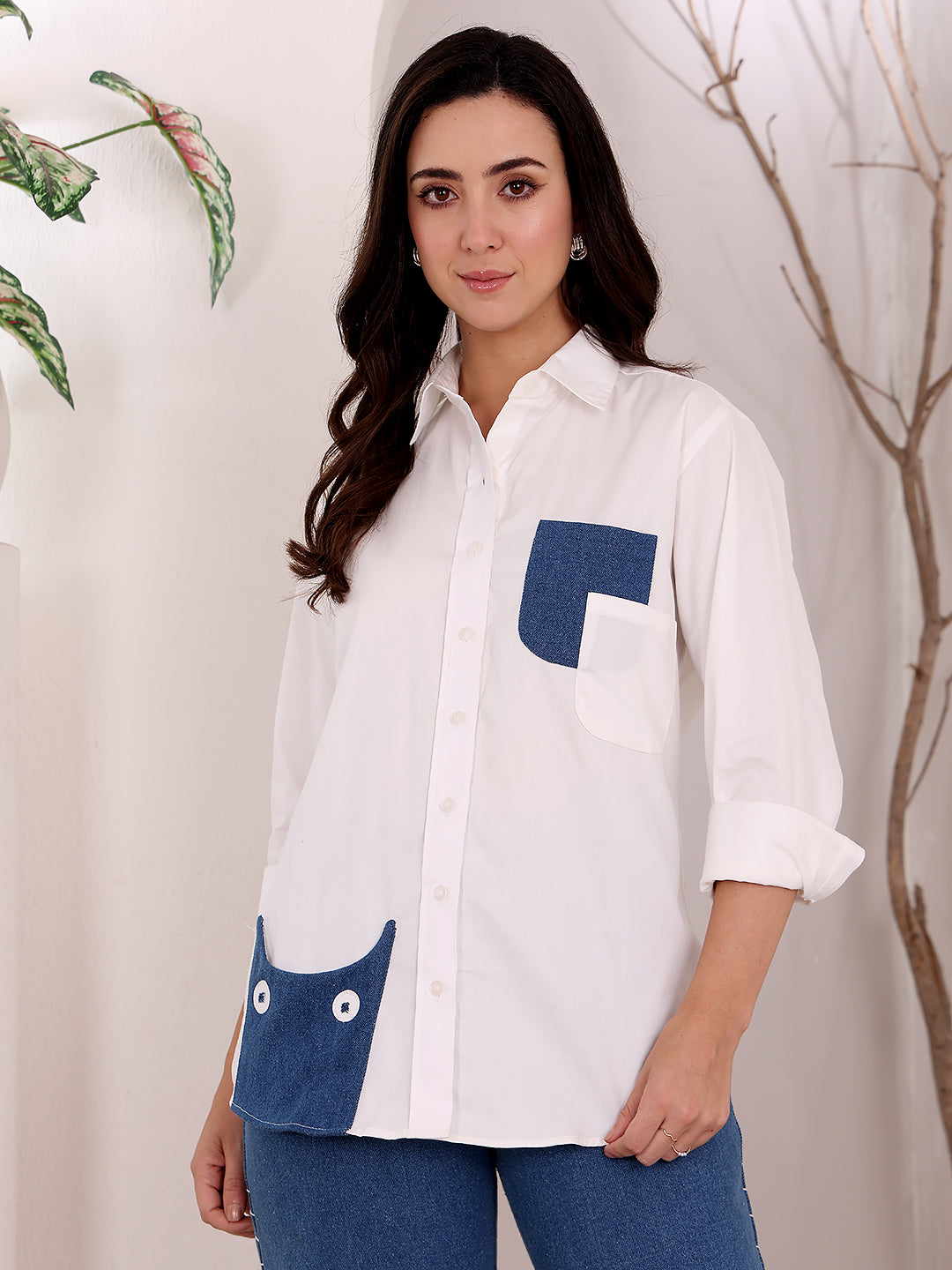 Woman wearing a white shirt with blue pocket accents against a neutral background
