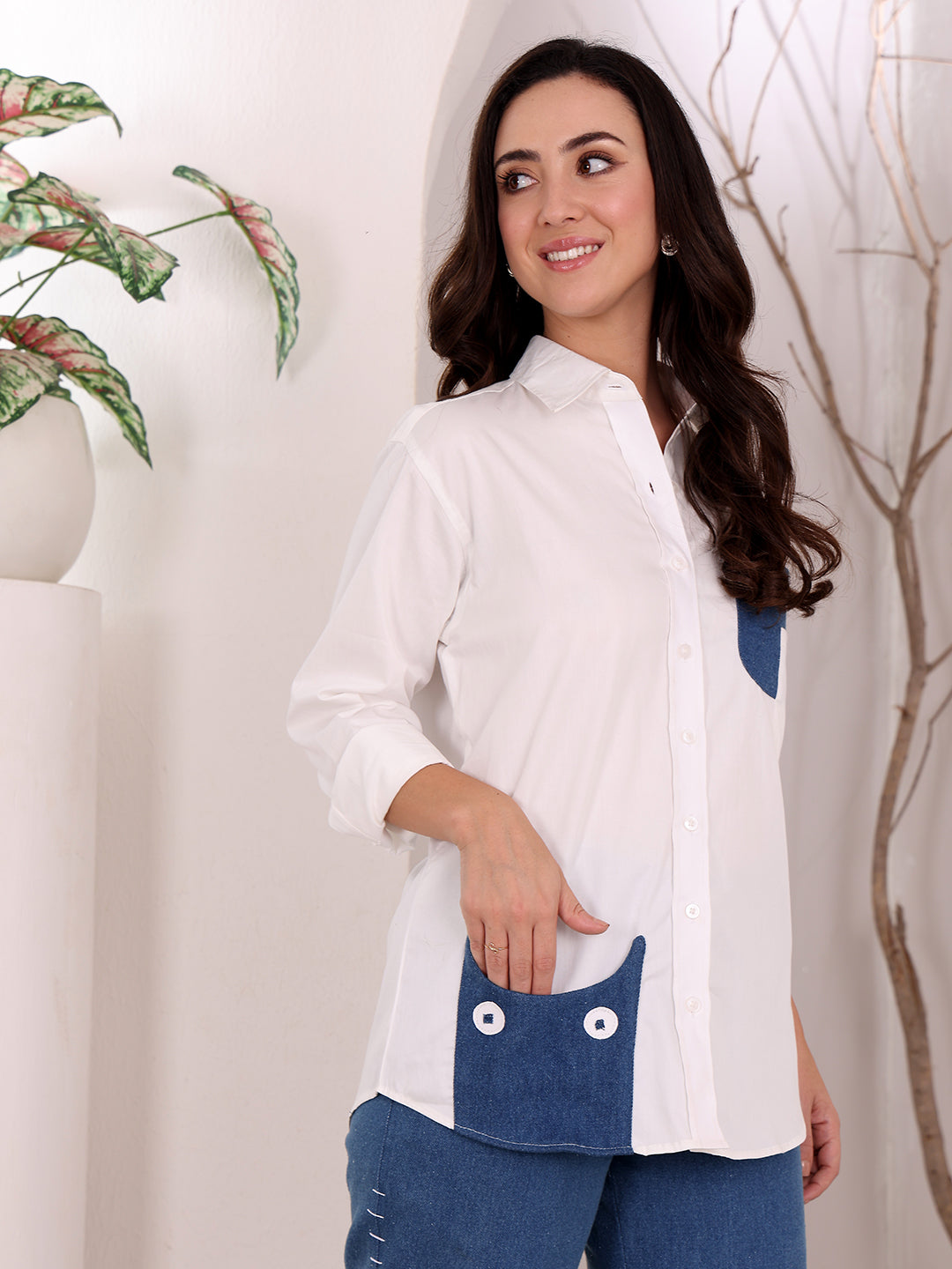 Woman wearing a white shirt with blue denim accents against a neutral background