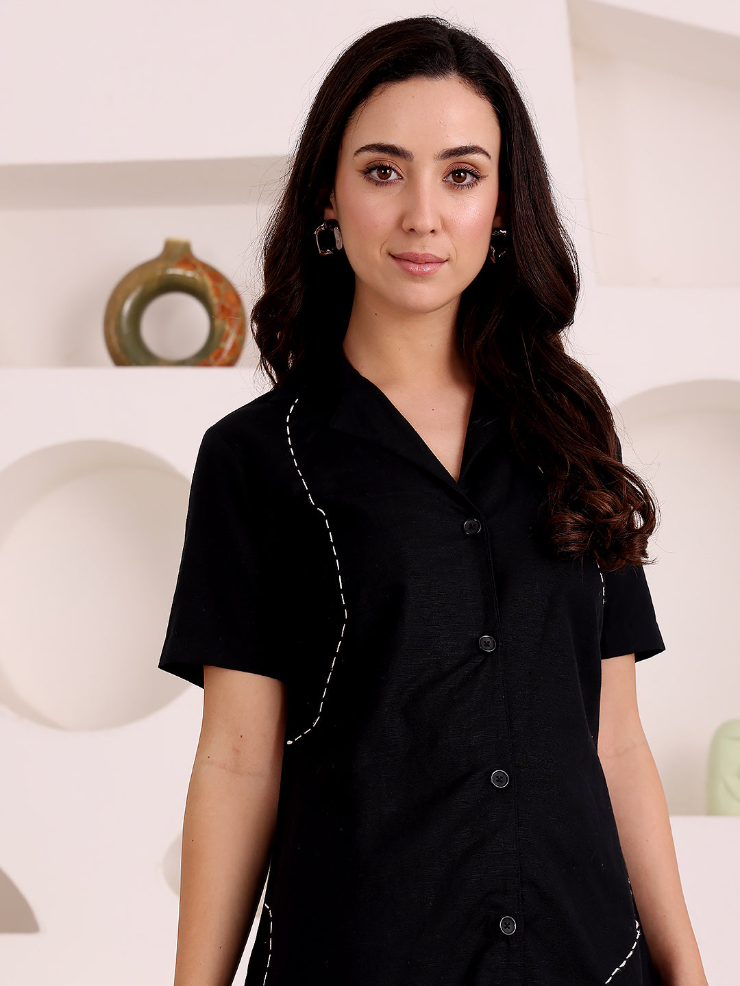 Woman wearing a black outfit with white trim against a white background