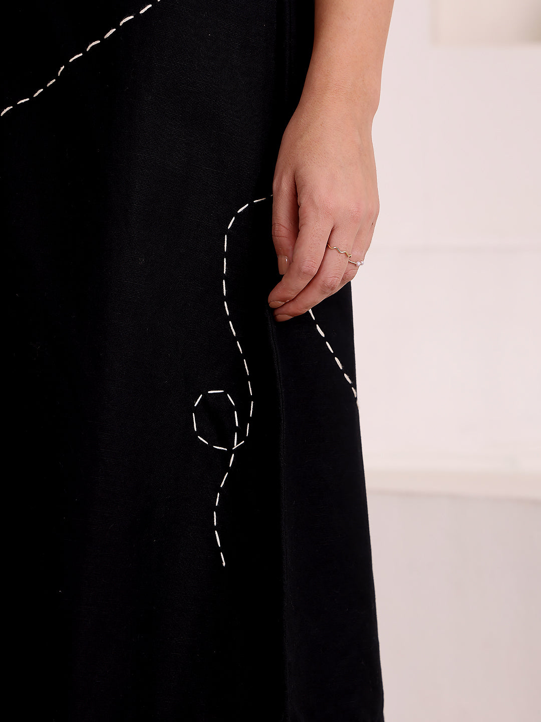 Black dress with white embroidery on a plain background