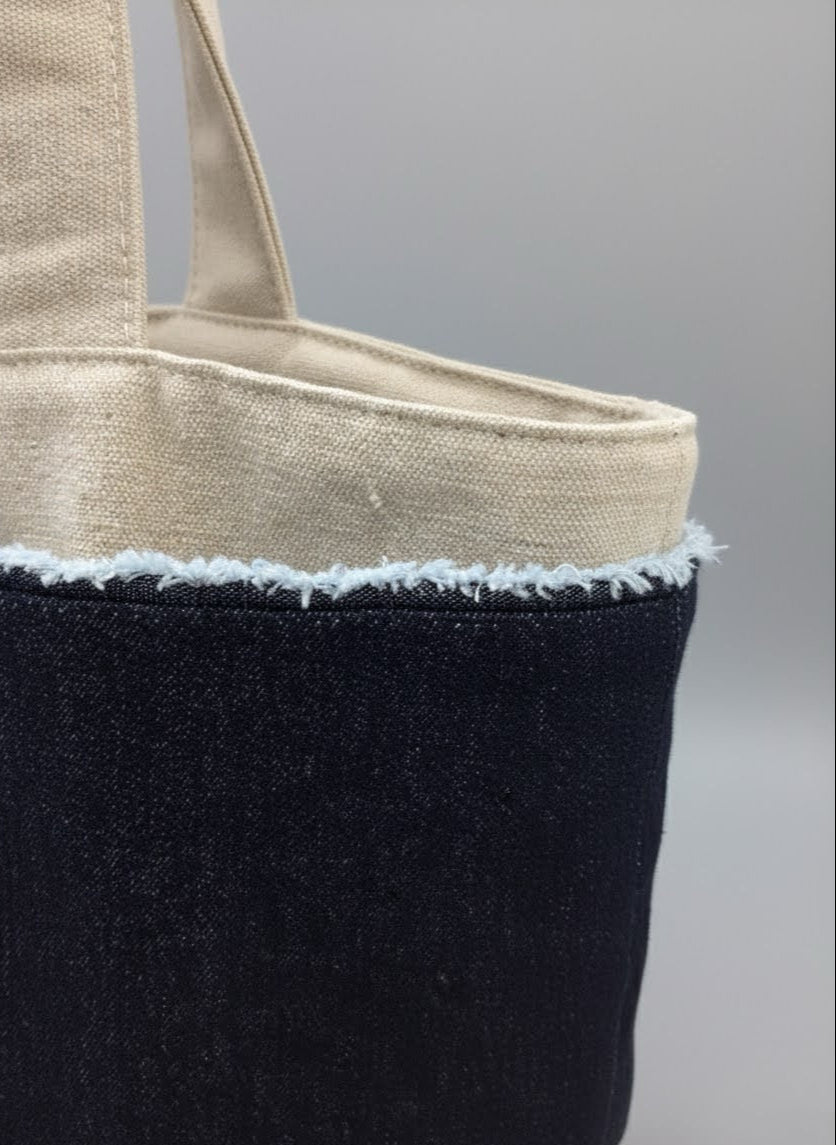 Tote bag with black body and beige top section on a gray background