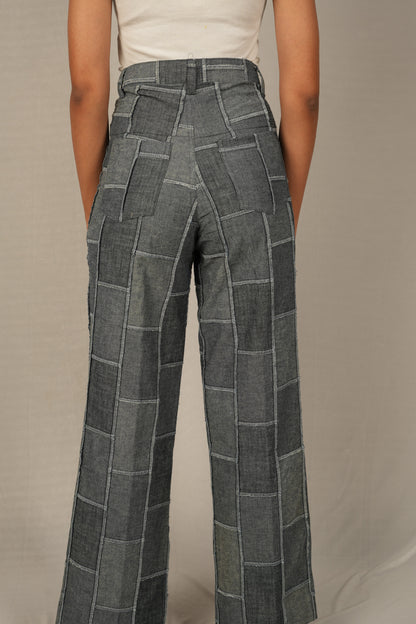 Person wearing patchwork denim pants against a neutral background