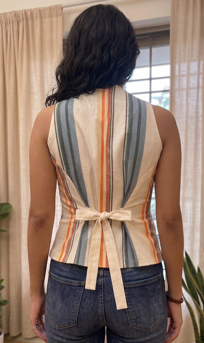 Person wearing a sleeveless striped top with a belt in an indoor setting