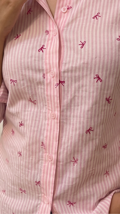 Pink and white striped shirt with bow patterns worn by a person.