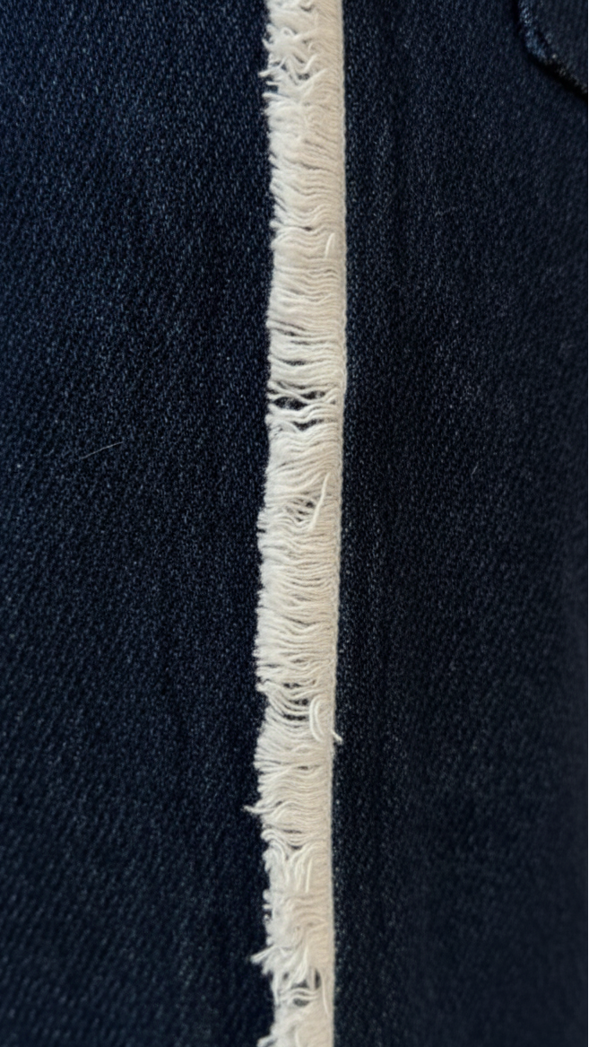 Close-up of a navy blue fabric with a white frayed edge