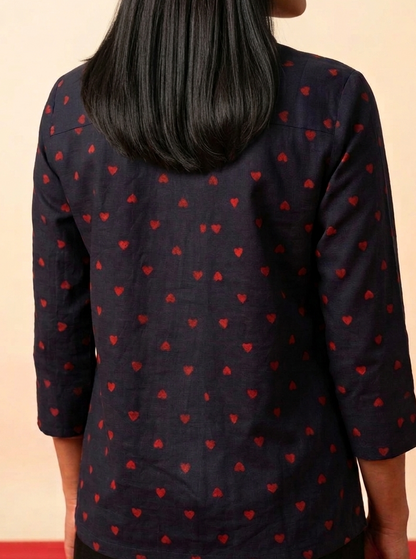 Navy blue shirt with red heart patterns worn by a person on a beige background