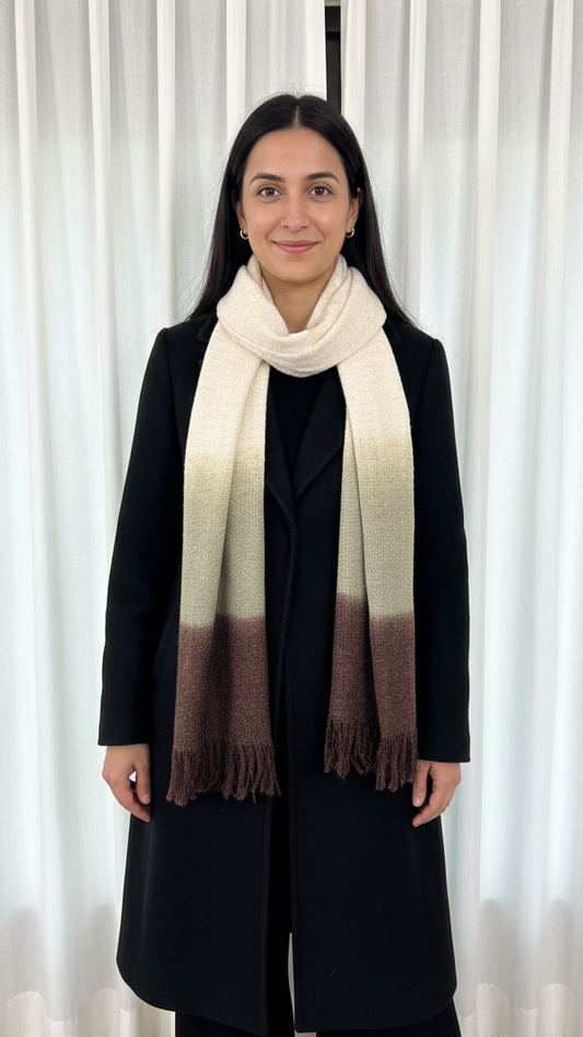 Person wearing a long coat and a scarf with a white curtain background