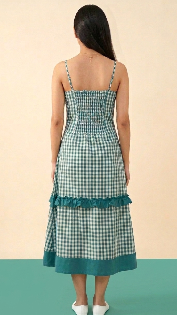 Woman wearing a green checkered dress with ruffled hem on a beige and green background