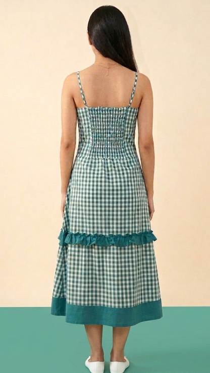 Woman wearing a green checkered dress with ruffled hem on a beige and green background