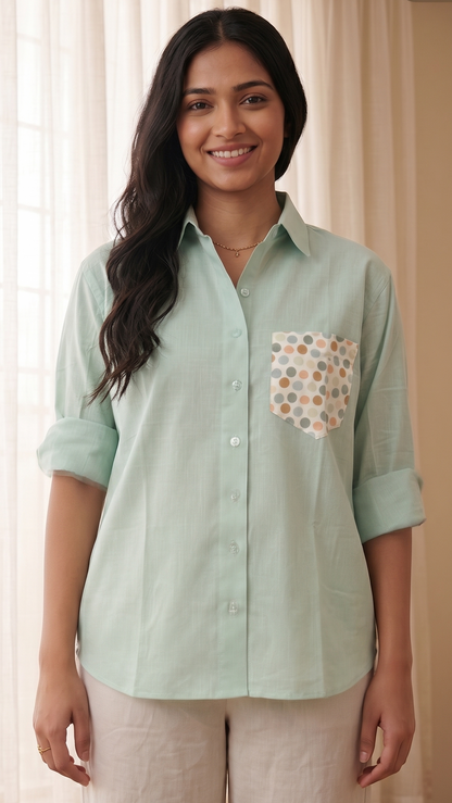 Woman wearing a light green shirt with a pocket design against a neutral background