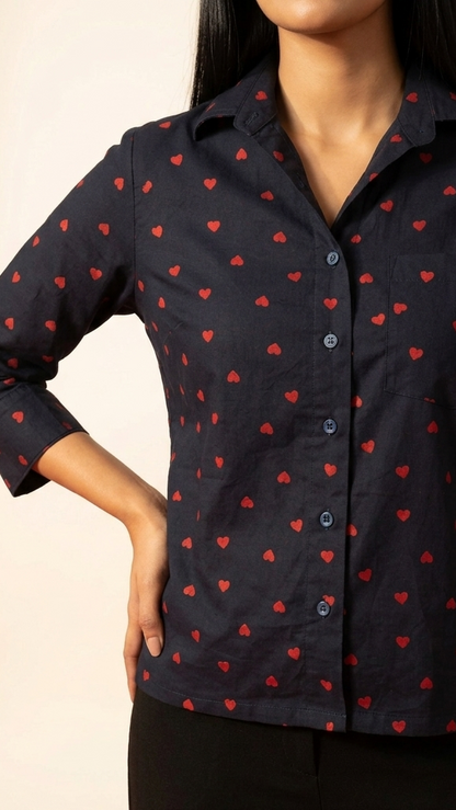 Woman wearing a navy blue shirt with red heart patterns on a beige background
