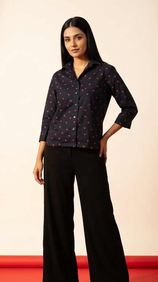 Woman wearing a black patterned shirt and black pants on a red and beige background