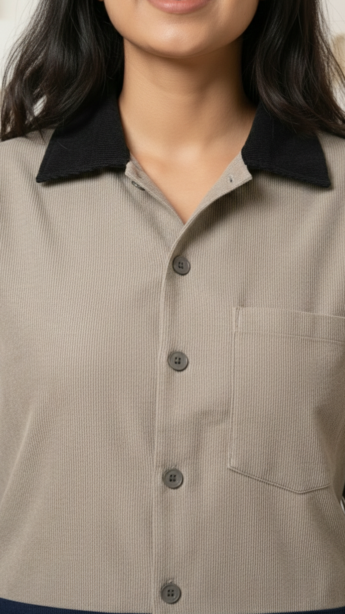 Person wearing a beige shirt with black collar and buttons