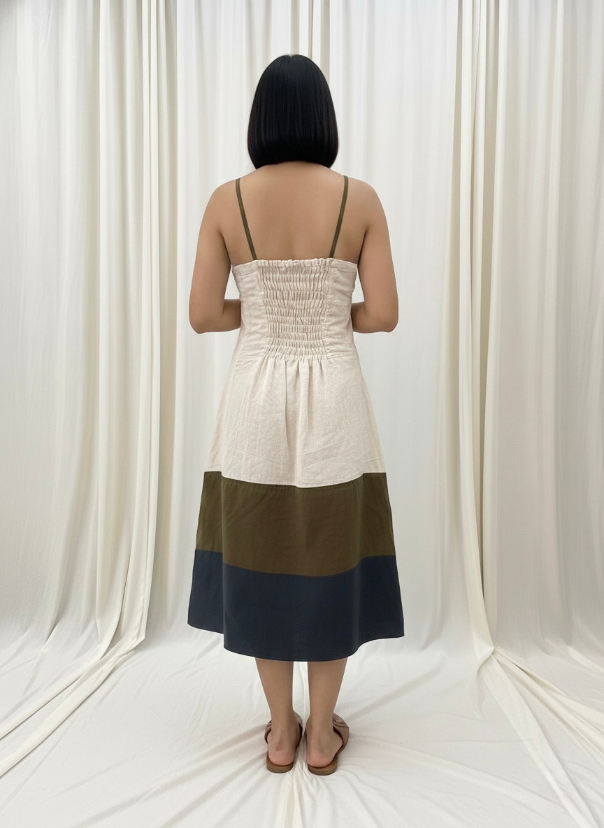 Woman wearing a two-tone dress with a white top and black bottom against a white curtain background