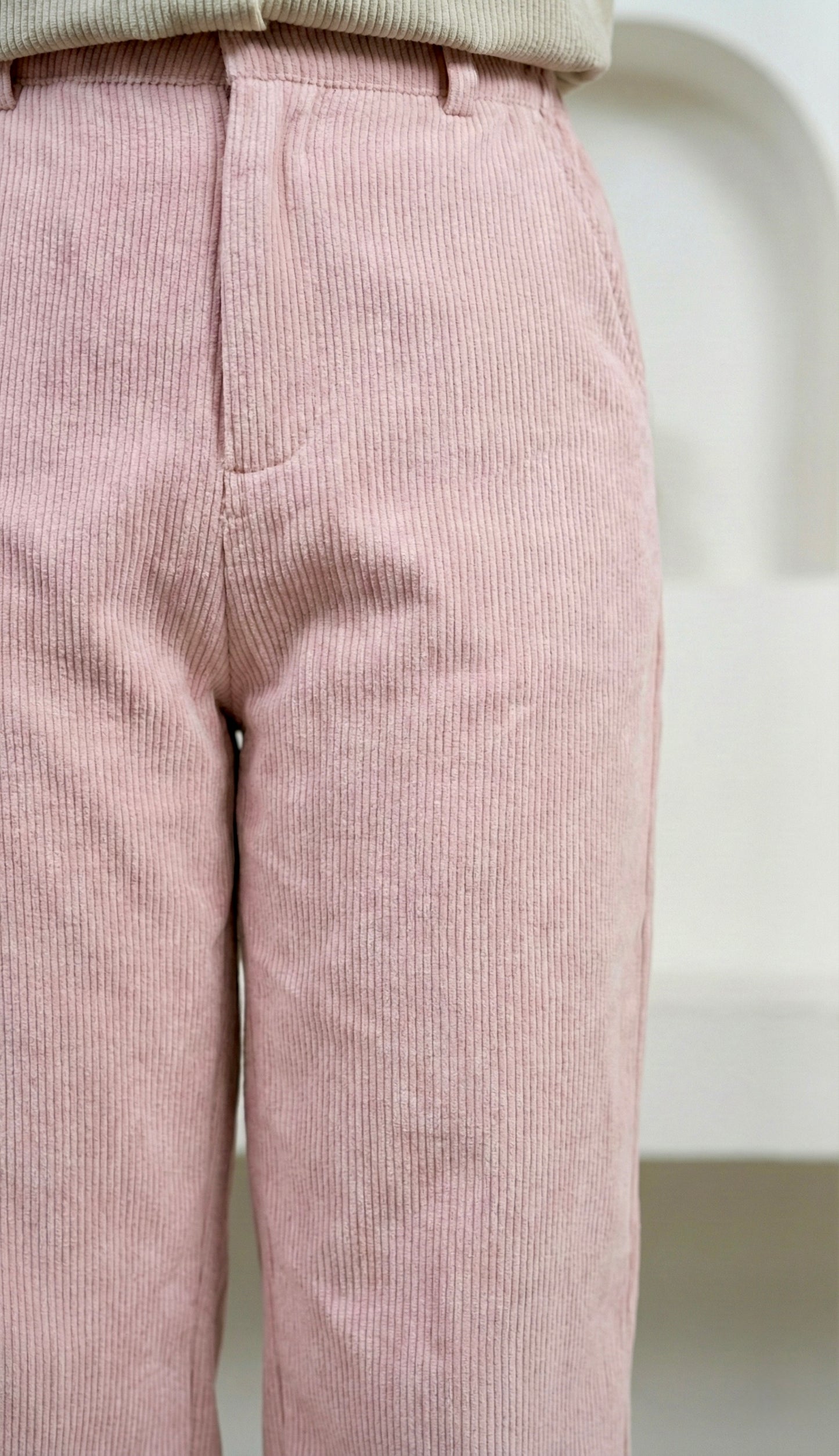 Pink corduroy pants with a visible stain on a white background