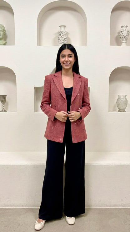 Woman wearing a pink blazer and black pants in a room with shelves displaying vases.