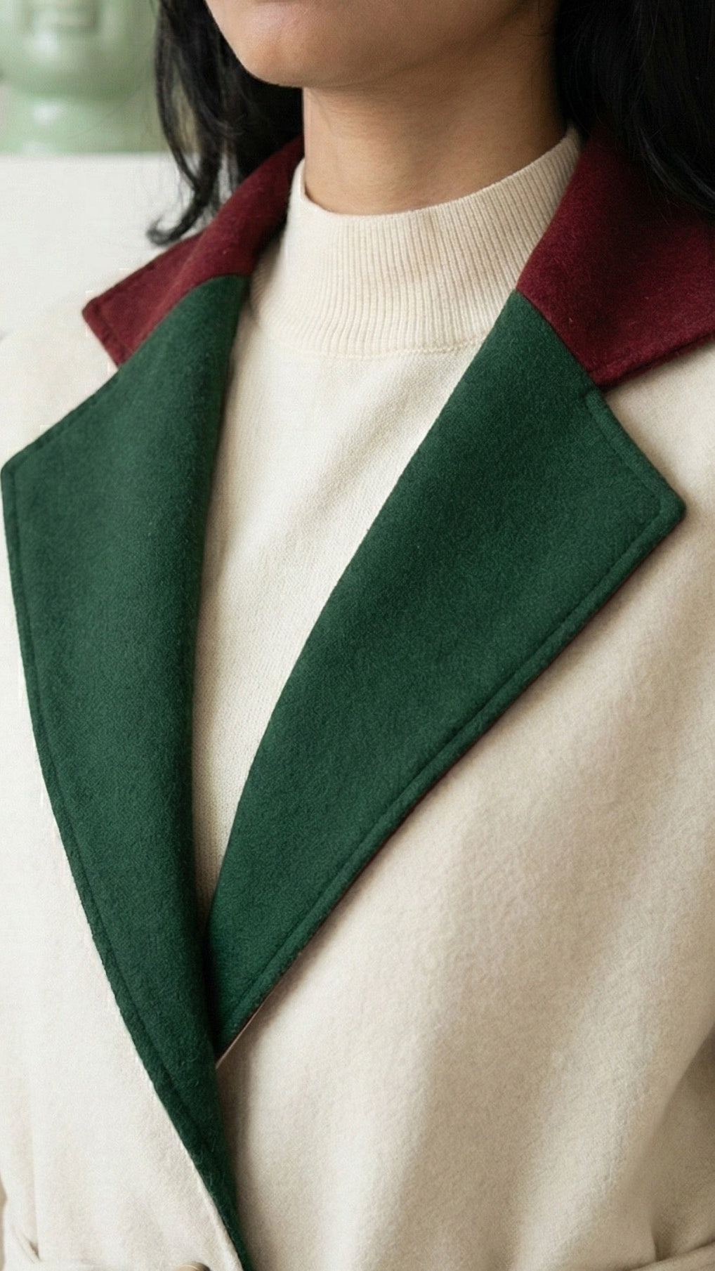 Person wearing a beige coat with green lapels and a red collar.