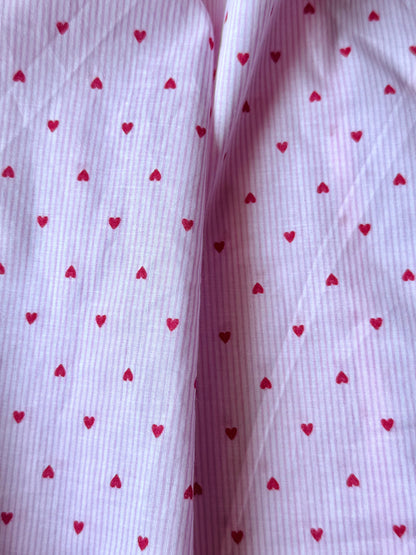 Close-up of fabric with red heart patterns on a white background