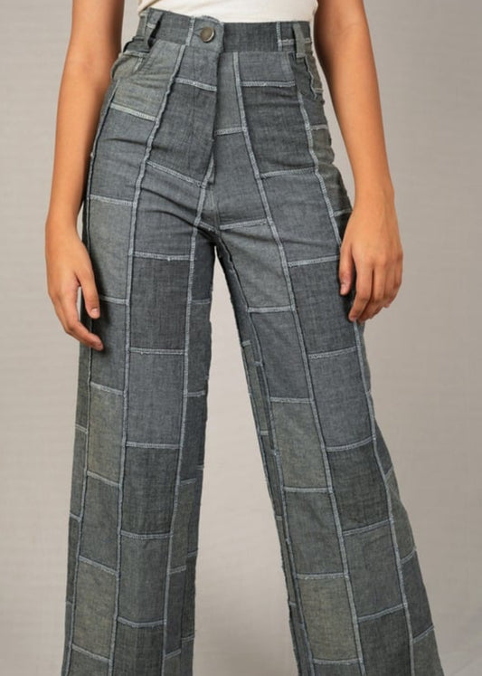 Plaid patchwork denim pants worn by a person on a plain background