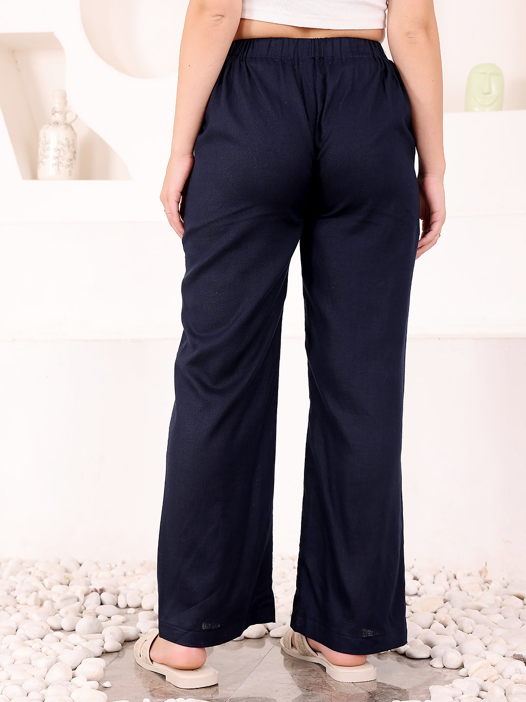 Navy blue wide-leg pants worn by a person on a pebble surface.
