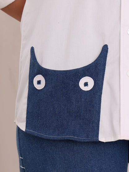 Close-up of a white shirt with blue denim pocket and white buttons on a beige background
