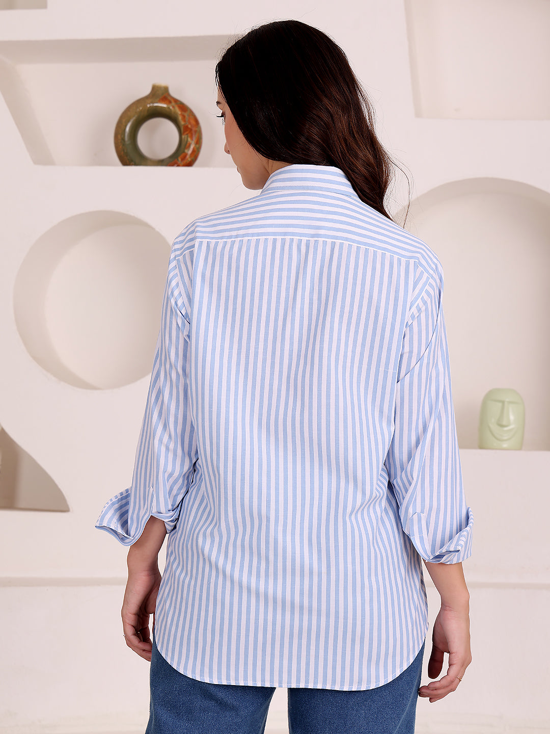 Woman wearing a blue and white striped shirt in a minimalistic room.