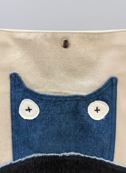 Close-up of a fabric pouch with blue cat face design on beige background